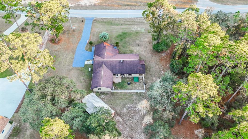 An aerial view shows a house with a brown roof, a blue driveway, and surrounding trees — 5518 N ELKCAM BOULEVARD, BEVERLY HILLS, FL