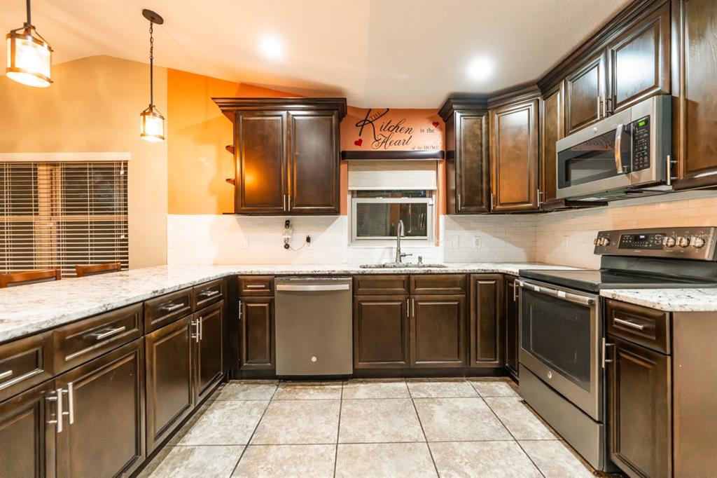 A kitchen features dark wood cabinets, granite countertops, stainless steel appliances, and orange accent walls — 5518 N ELKCAM BOULEVARD, BEVERLY HILLS, FL