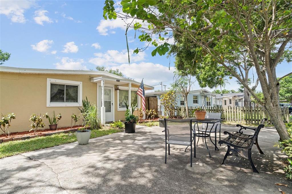 A beige house exterior features a concrete patio with outdoor furniture and a large tree — 4530 72ND AVENUE N, PINELLAS PARK, FL