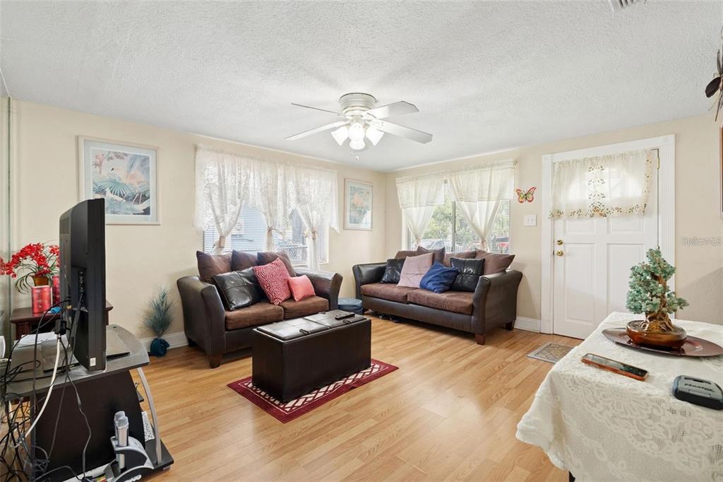 A living room features two brown sofas, a ceiling fan, and light wood flooring — 4530 72ND AVENUE N, PINELLAS PARK, FL