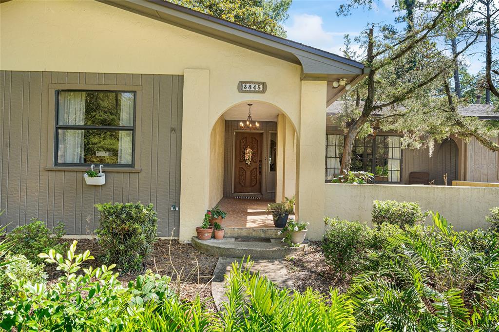 The exterior of a house features a tan stucco entryway with a wooden front door — 3845 NW 37TH PLACE, GAINESVILLE, FL