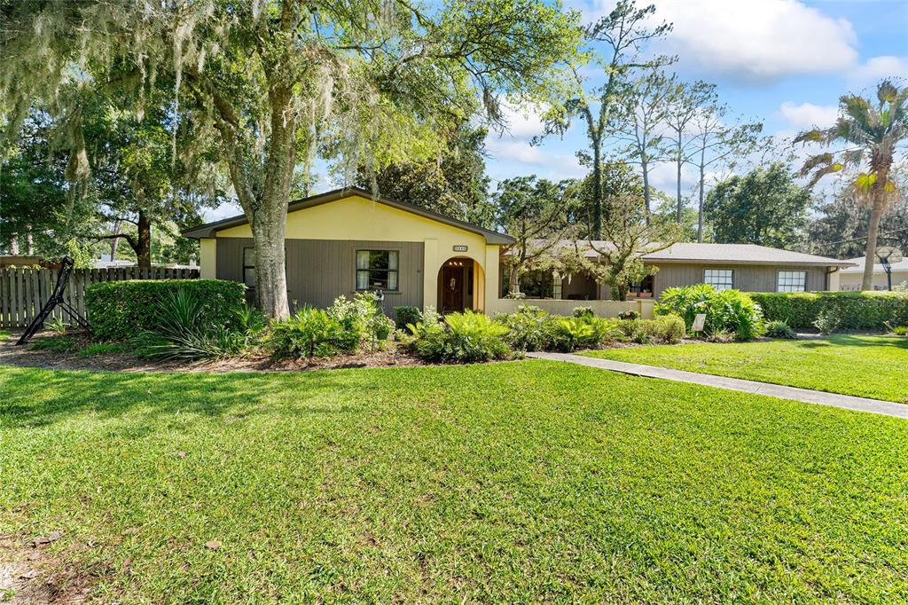 A single-story house with yellow and brown siding sits behind a large, grassy front yard — 3845 NW 37TH PLACE, GAINESVILLE, FL