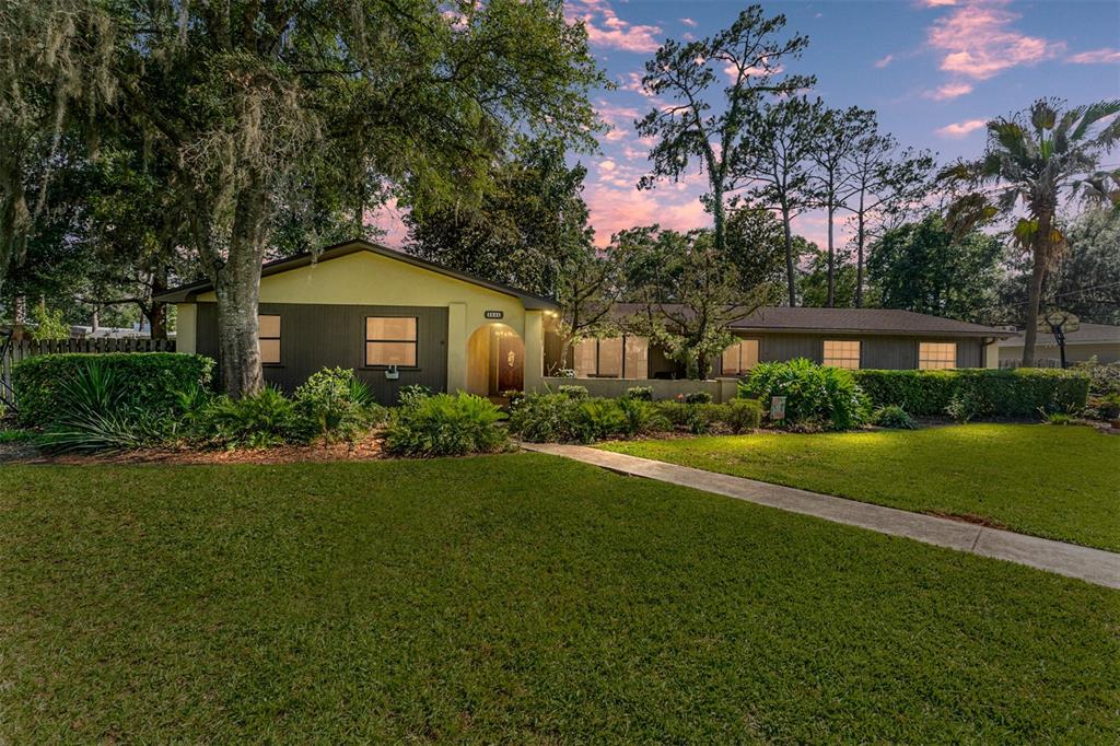 A single-story house with a yellow and brown exterior sits behind a large green lawn — 3845 NW 37TH PLACE, GAINESVILLE, FL