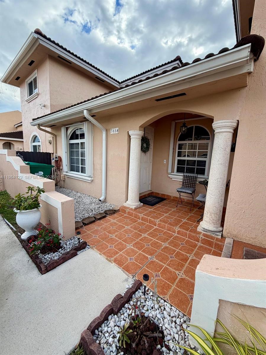 The exterior of a peach-colored house features a tiled entryway with two white columns — 3858 SW 153rd Pl, Miami FL 33185, MIAMI, FL