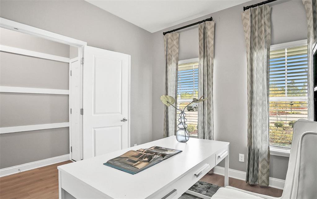 A home office features a white desk, light wood floors, gray walls, and two windows — 765 PINTAIL TERRACE, ORANGE PARK, FL