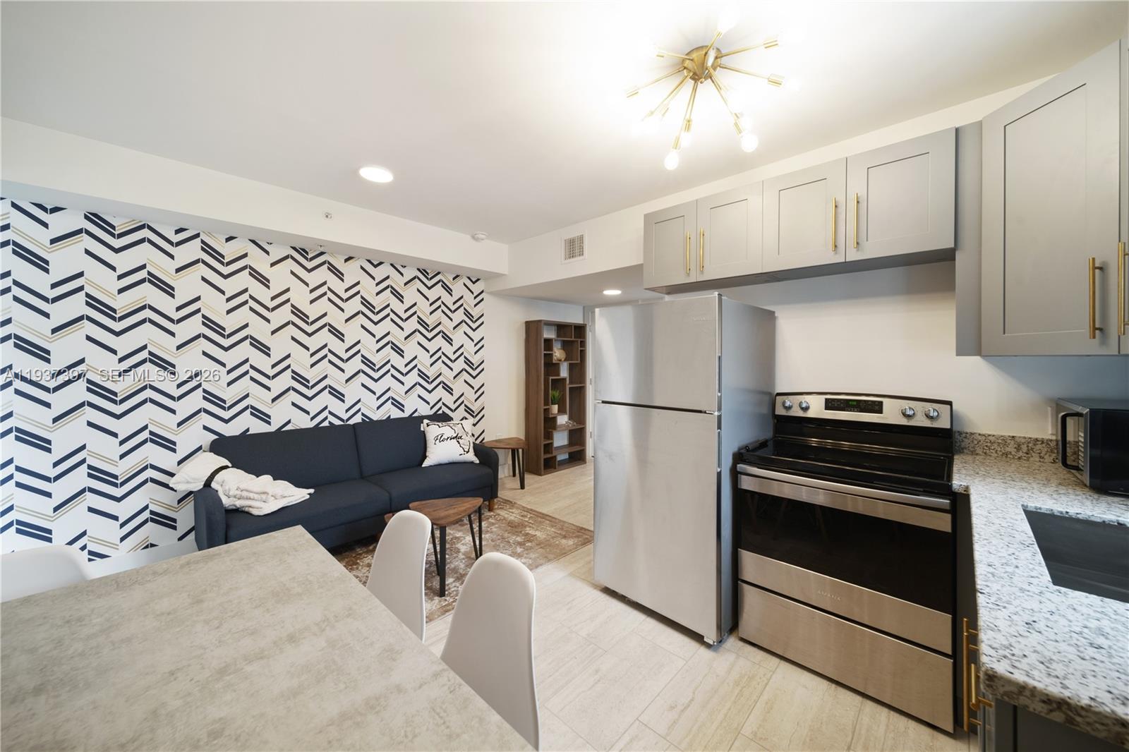 A kitchen and living area featuring grey cabinets, stainless steel appliances, and patterned wallpaper — 2162 SW 14th Ter # 101, Miami FL 33145, MIAMI, FL