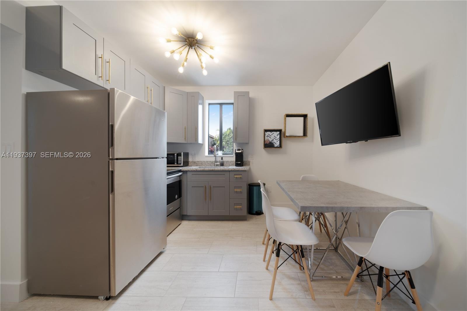 A kitchen features gray cabinets, stainless steel appliances, a dining table, and a wall-mounted television — 2162 SW 14th Ter # 101, Miami FL 33145, MIAMI, FL