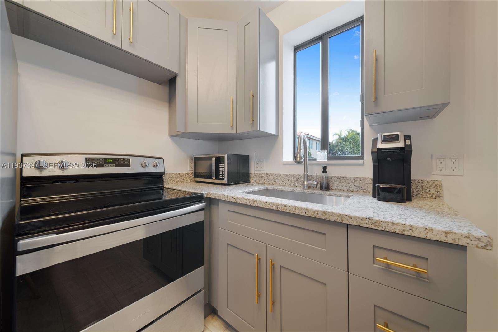 A kitchen features gray cabinets, gold hardware, granite countertops, and stainless steel appliances — 2162 SW 14th Ter # 101, Miami FL 33145, MIAMI, FL