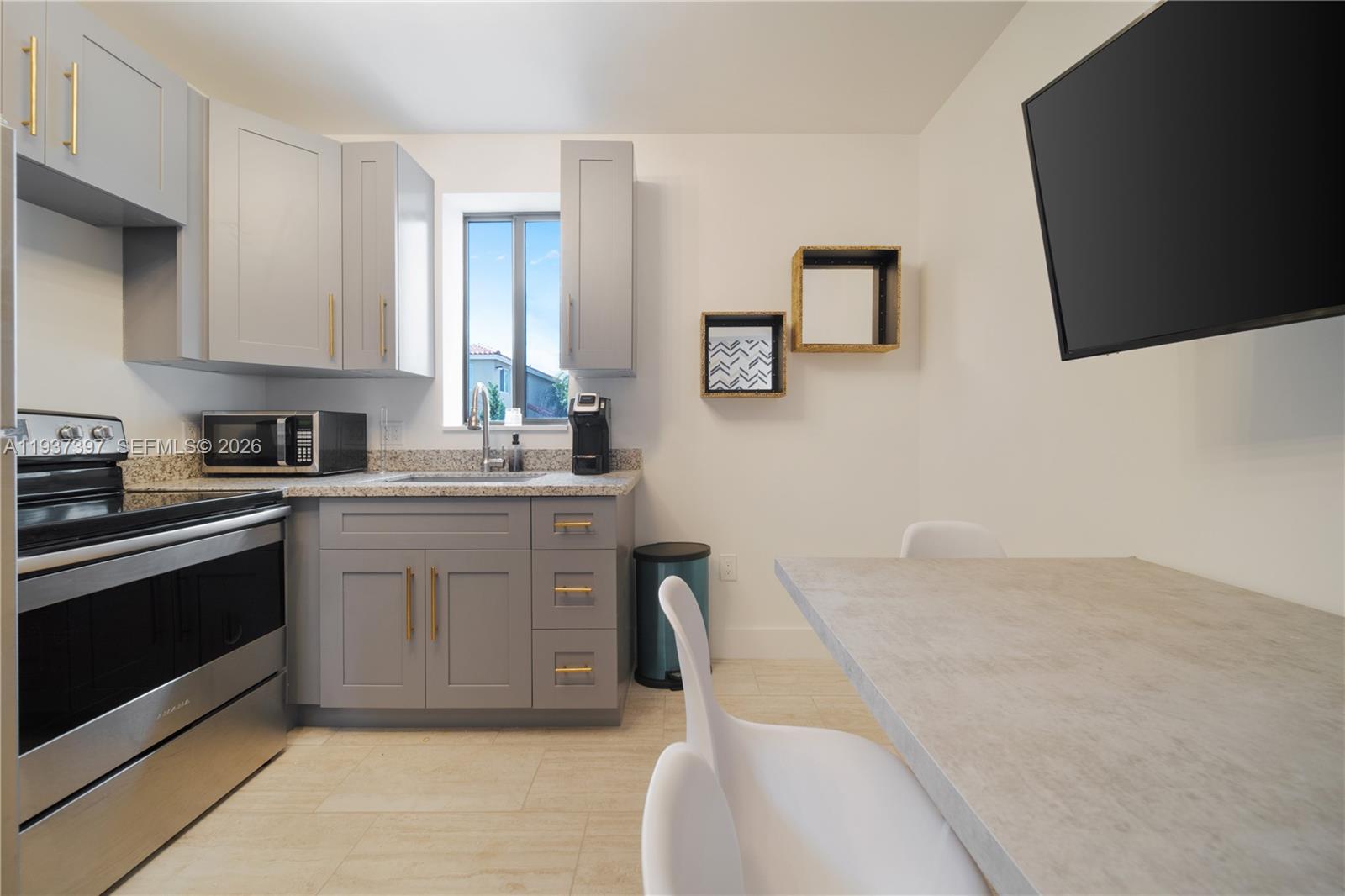 A kitchen features gray cabinets with gold hardware, stainless steel appliances, and a dining area — 2162 SW 14th Ter # 101, Miami FL 33145, MIAMI, FL