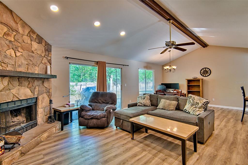 A living room features a stone fireplace, a gray sectional sofa, and wood-look flooring — 4347 NW 43RD TERRACE, GAINESVILLE, FL