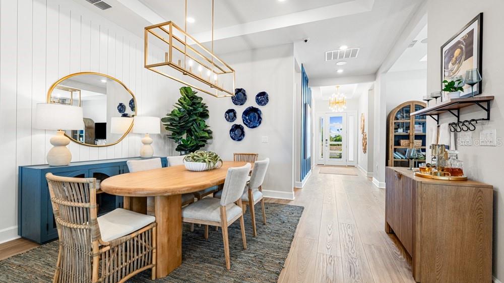 A dining room features a wooden table, rattan chairs, a blue sideboard, and a gold chandelier — 10606 ECLIPSE STREET, SARASOTA, FL
