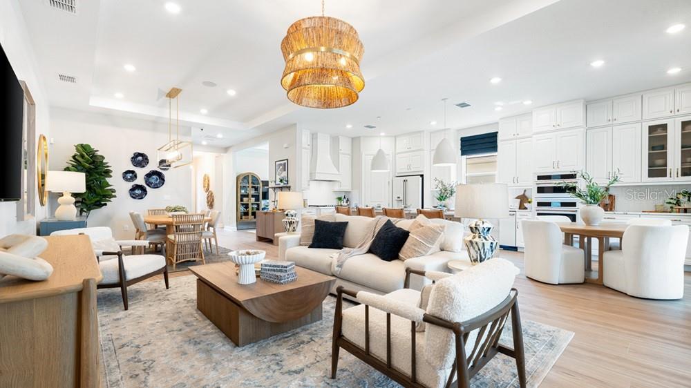 An open-concept living and dining area features white cabinetry, a large kitchen island, and furniture — 10606 ECLIPSE STREET, SARASOTA, FL