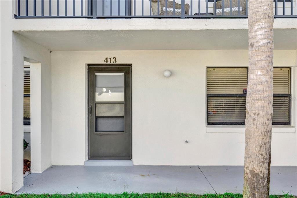 The exterior view shows a ground-level apartment entrance with a screen door and windows — 2150 ATLANTIC STREET UNIT 413, MELBOURNE BEACH, FL