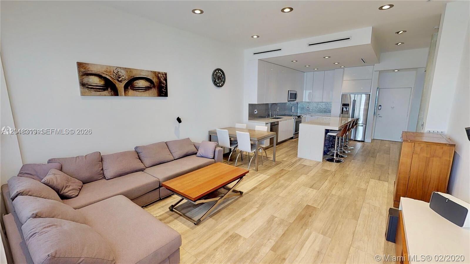 An open-concept living room and kitchen feature light wood flooring and modern white cabinetry — 3725 S Ocean Dr, Hollywood FL 33019, HOLLYWOOD, FL