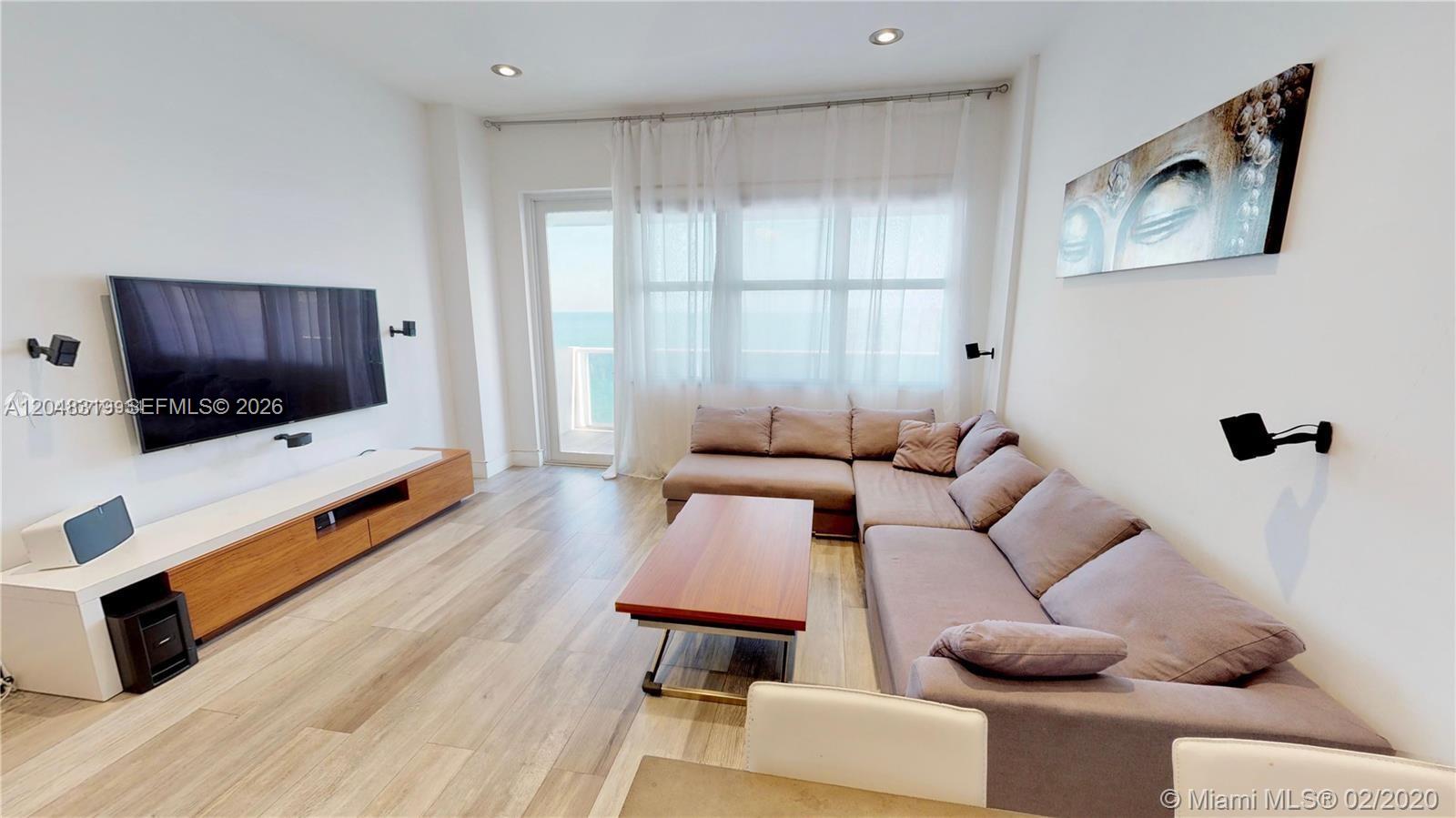 A living room features a large sectional sofa, a wall-mounted television, and wood-look flooring — 3725 S Ocean Dr, Hollywood FL 33019, HOLLYWOOD, FL