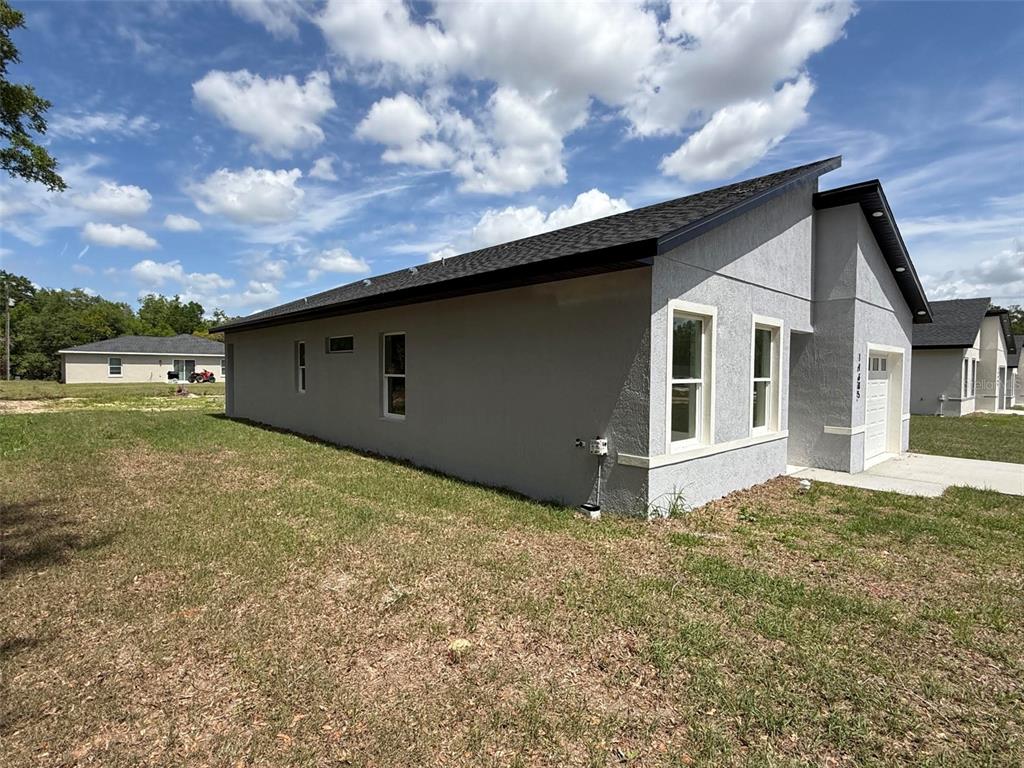 A side view of a gray, single-story house with a dark roof and a garage — 14685 SW 22 PLACE, OCALA, FL