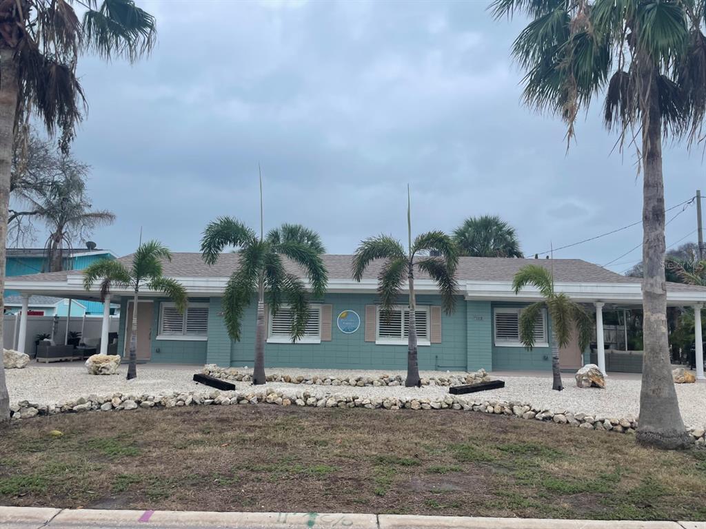 A single-story teal house with a covered porch, palm trees, and a gravel front yard — 720 E GULF BOULEVARD UNIT B, INDIAN ROCKS BEACH, FL