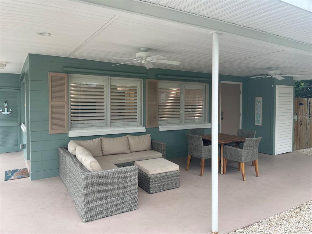 A covered outdoor patio features a gray wicker sectional sofa, dining set, and ceiling fans — 720 E GULF BOULEVARD UNIT B, INDIAN ROCKS BEACH, FL