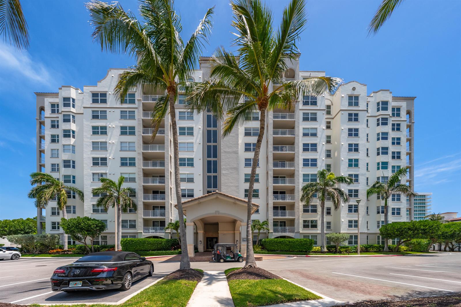 A multi-story white residential building with palm trees and a car in the foreground — 3594 S Ocean Boulevard # 604, Highland Beach FL 33487, HIGHLAND BEACH, FL