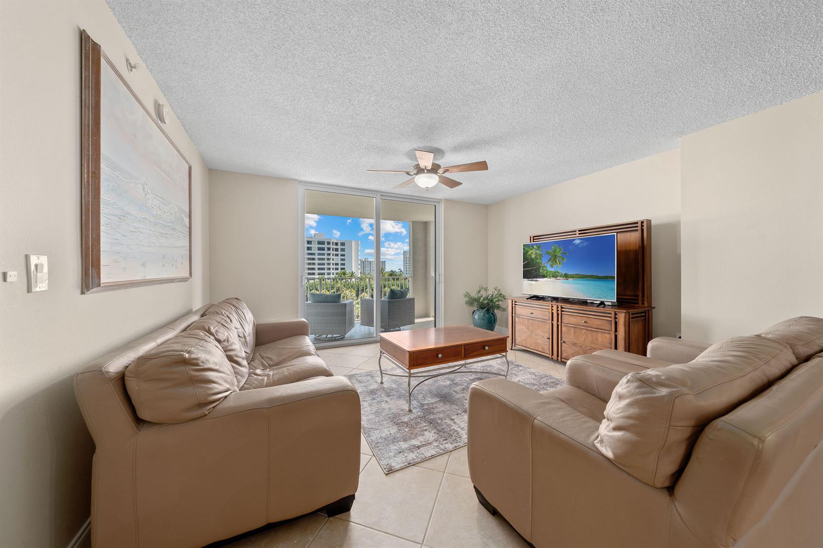A living room features beige leather sofas, a wooden media console, and a balcony view — 3594 S Ocean Boulevard # 604, Highland Beach FL 33487, HIGHLAND BEACH, FL