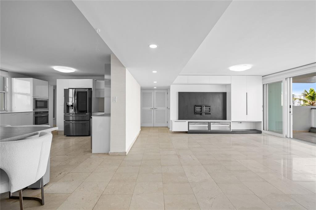 A modern, open-concept living area with white cabinetry, tile flooring, and a large media wall — #6 MARIANO RAMÍREZ BAGES UNIT 1, SAN JUAN, PR
