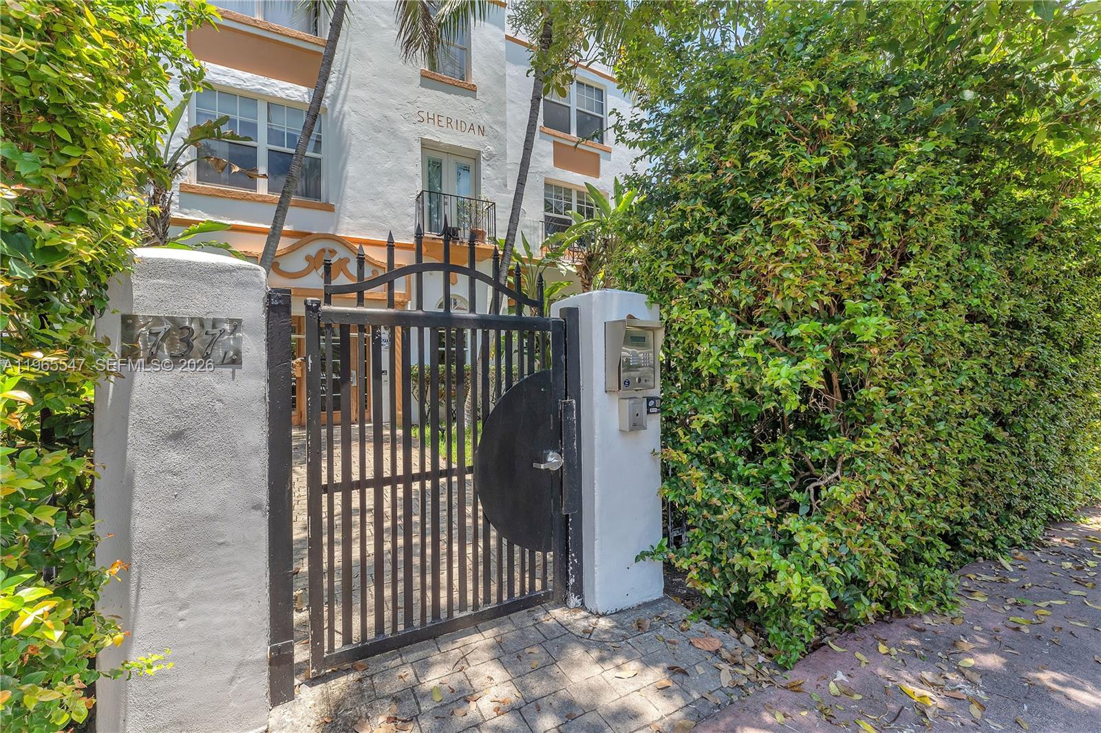 A black metal gate stands before a white multi-story building labeled Sheridan — 737 Jefferson Ave # 305, Miami Beach FL 33139, MIAMI BEACH, FL