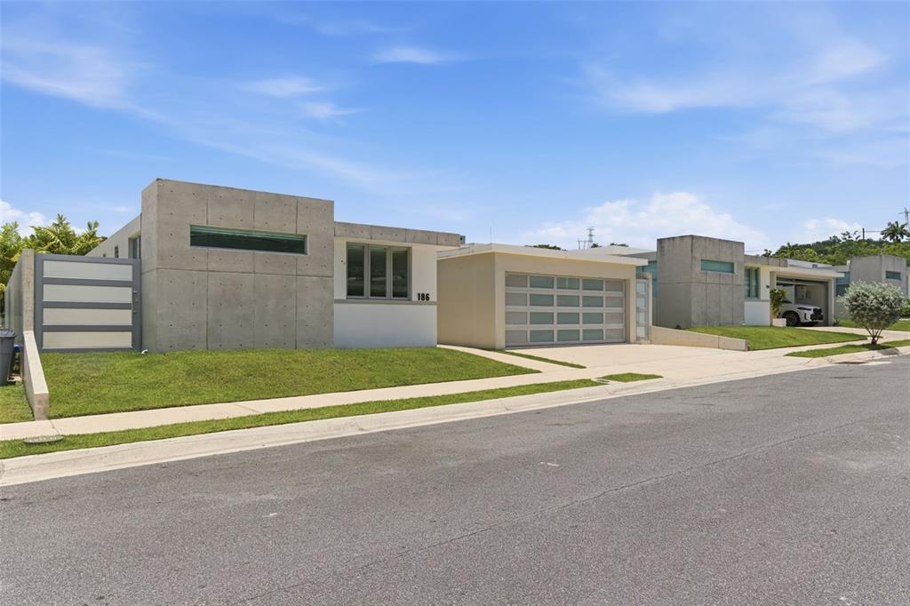 A modern single-story house with a concrete facade and a multi-paneled garage door — MONTECIELO LYRA ST., GUAYNABO, PR