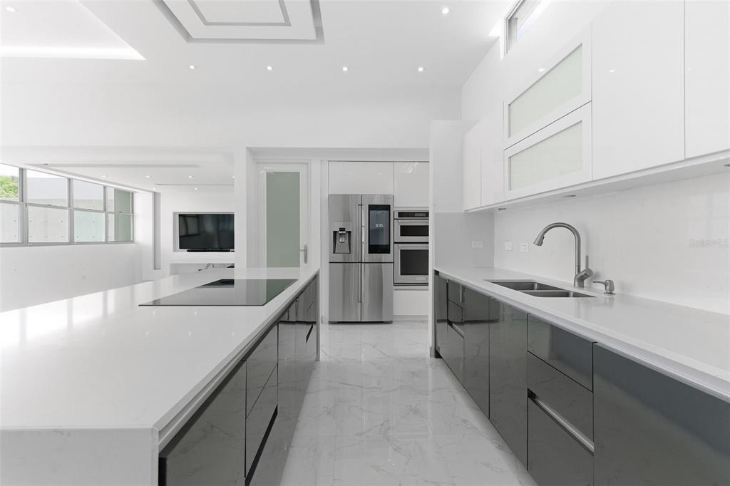 A modern kitchen features a white island, dark grey lower cabinets, and stainless steel appliances — MONTECIELO LYRA ST., GUAYNABO, PR