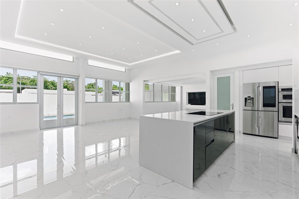 A modern white kitchen features a large island, stainless steel appliances, and marble-look tile flooring — MONTECIELO LYRA ST., GUAYNABO, PR