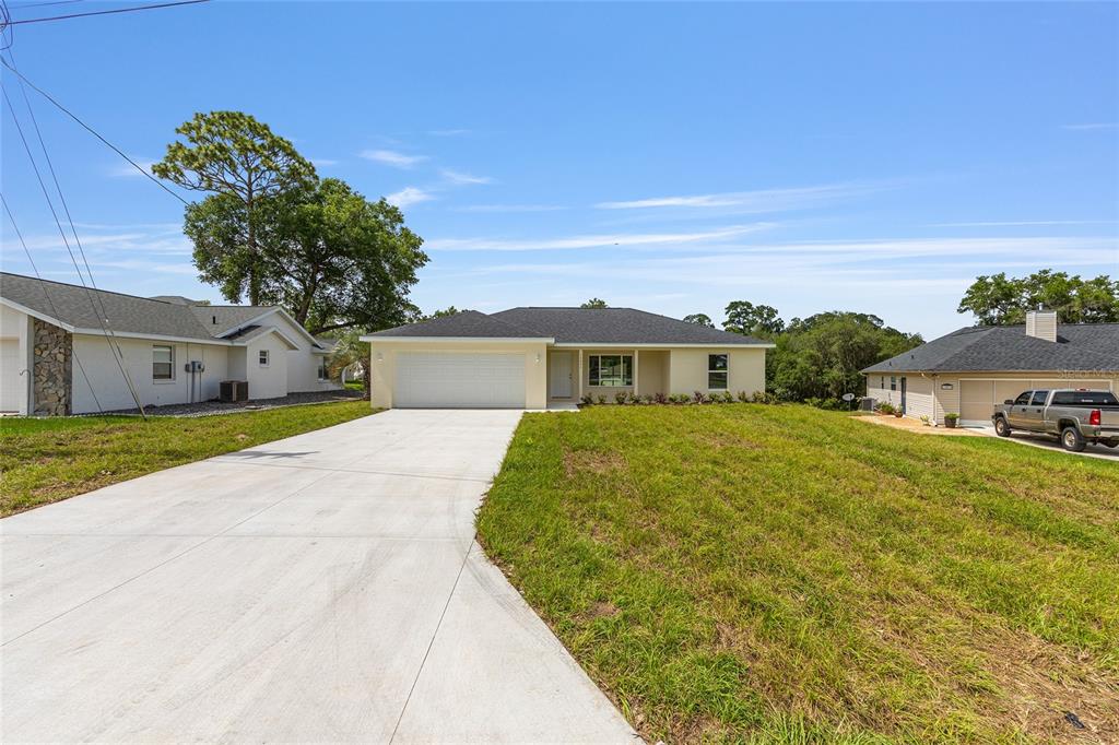 A single-story house with a white garage, light-colored siding, and a concrete driveway — 62 MALAUKA RADIAL, OCKLAWAHA, FL