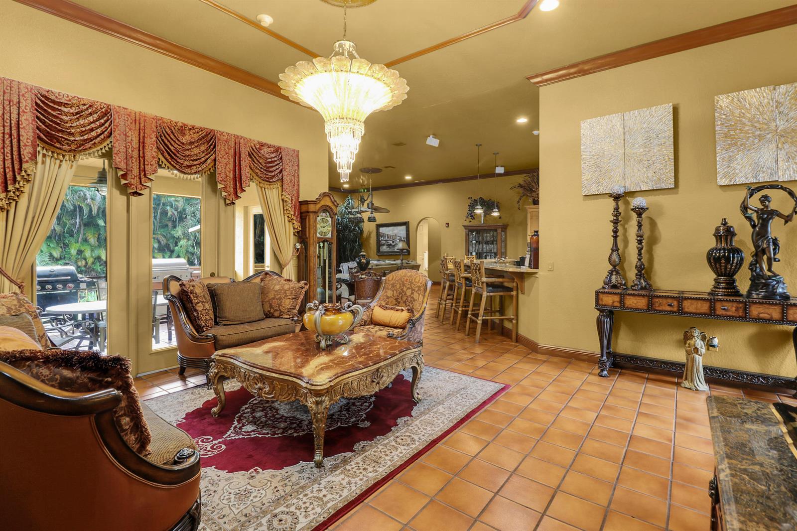 A living room with tile floors, a crystal chandelier, ornate furniture, and a bar area — 7086 Hall Boulevard, FL 33470, FL