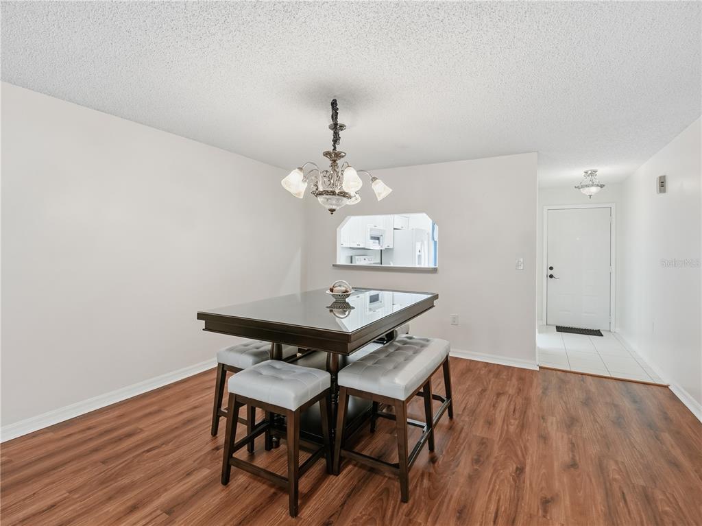 A dining area features a dark wood table with four stools, wood-look flooring, and chandelier — 914 MICHIGAN AVENUE, ST CLOUD, FL