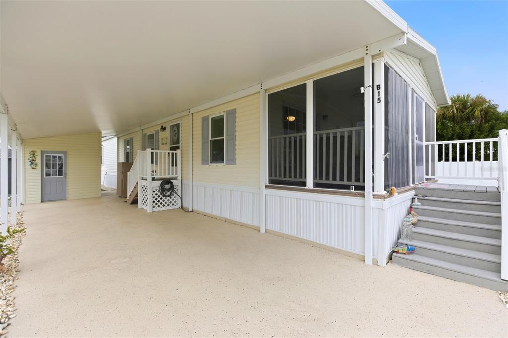 A mobile home exterior features a covered carport, a screened porch, and gray wooden steps — 15 N CARDINAL UNIT B15, PUNTA GORDA, FL