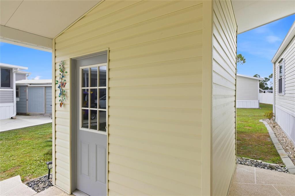A light yellow storage shed with a gray door stands on a concrete patio — 15 N CARDINAL UNIT B15, PUNTA GORDA, FL