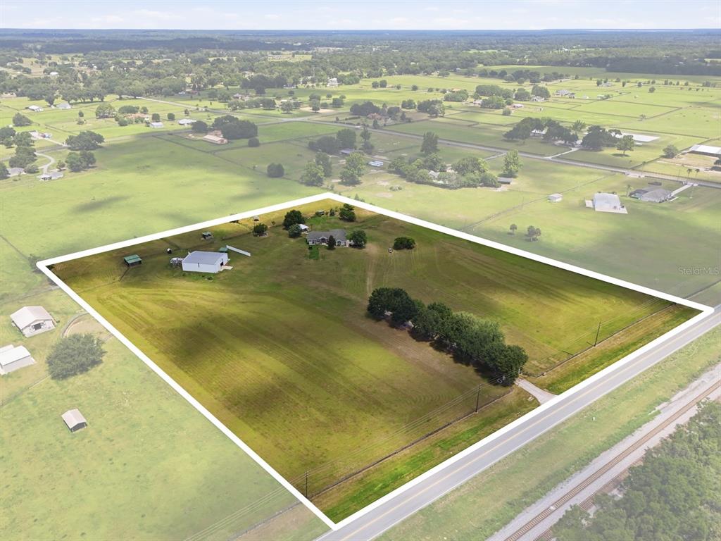 An aerial view shows a house and outbuildings on a large, fenced rural property — 11748 NE JACKSONVILLE ROAD, ANTHONY, FL