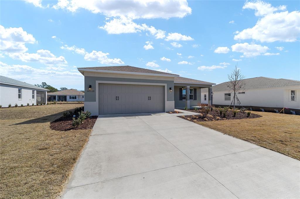 A single-story house with a two-car garage and a concrete driveway under a blue sky — 10339 SW 105TH TERRACE, OCALA, FL