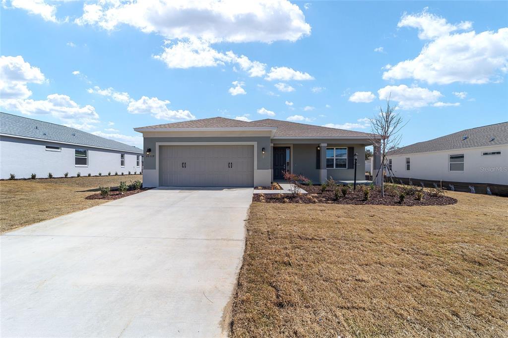 A single-story suburban house features a two-car garage, a concrete driveway, and a landscaped yard — 10339 SW 105TH TERRACE, OCALA, FL