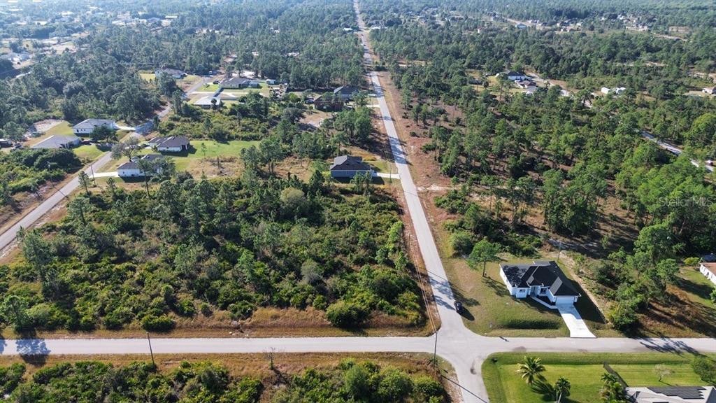 An aerial view shows a residential neighborhood with scattered houses surrounded by dense pine forests — 4400 E 5TH STREET, LEHIGH ACRES, FL
