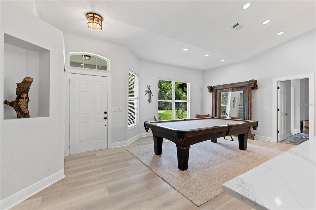 A room featuring a pool table, a kitchen with light cabinetry, and a large ornate mirror — 427 PENDREY DRIVE, PORT ORANGE, FL