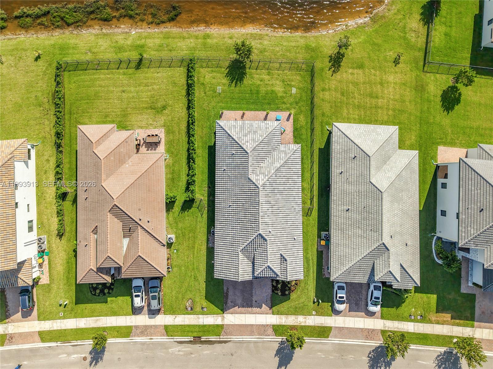 An aerial view shows three suburban houses with tiled roofs and driveways along a street — 5246 Karlia Drive, Ave Maria FL 34142, AVE MARIA, FL