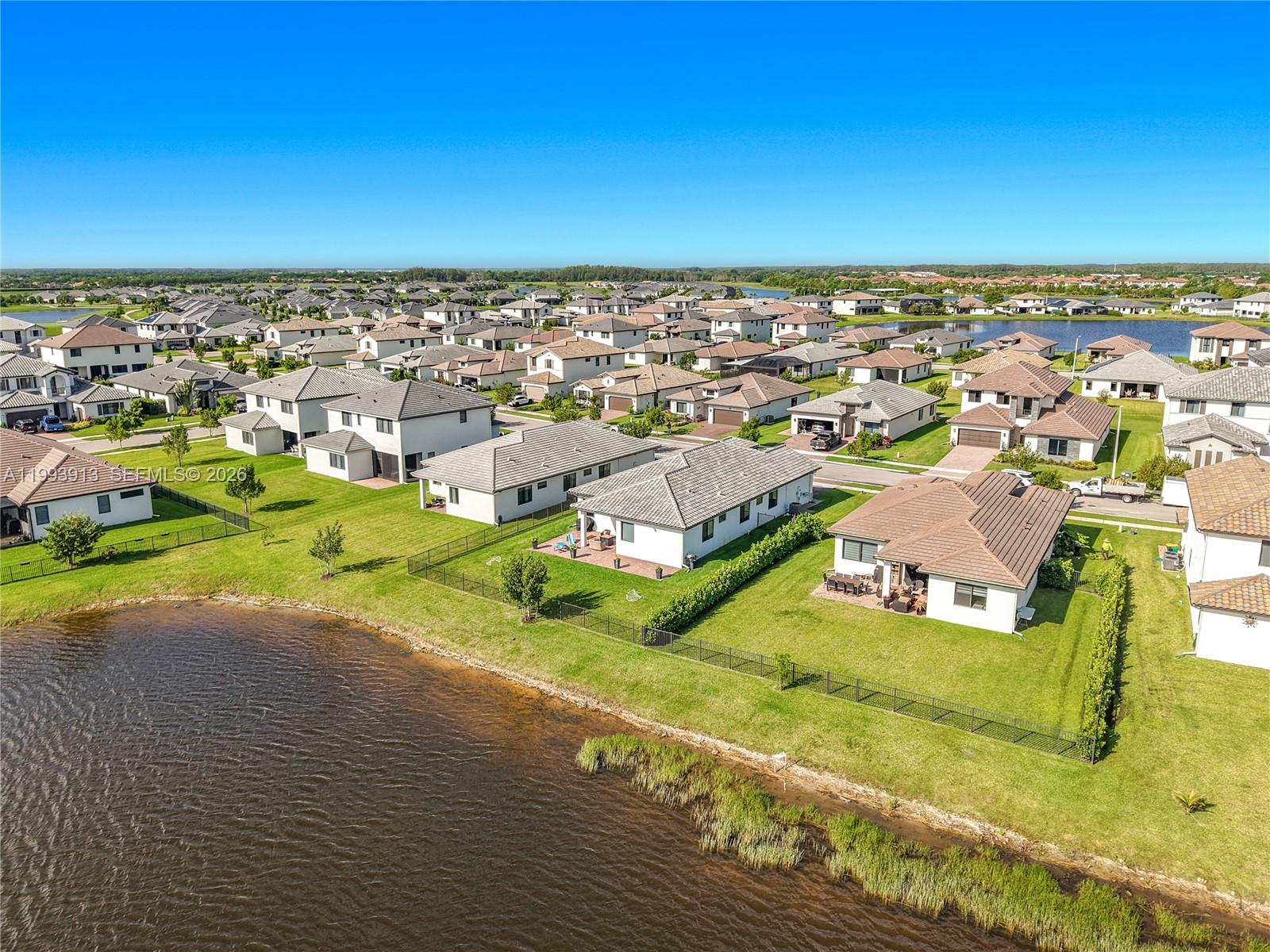 An aerial view shows a suburban neighborhood with houses bordering a lake — 5246 Karlia Drive, Ave Maria FL 34142, AVE MARIA, FL