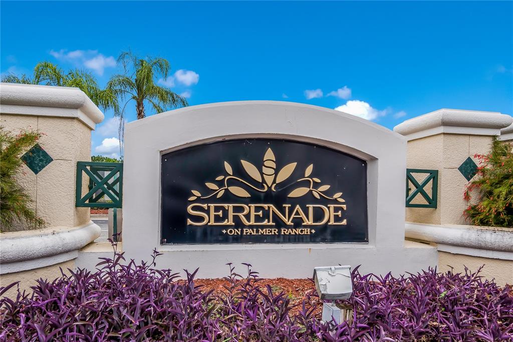 A sign for Serenade on Palmer Ranch stands behind purple plants against a blue sky — 5134 NORTHRIDGE ROAD UNIT 302, SARASOTA, FL