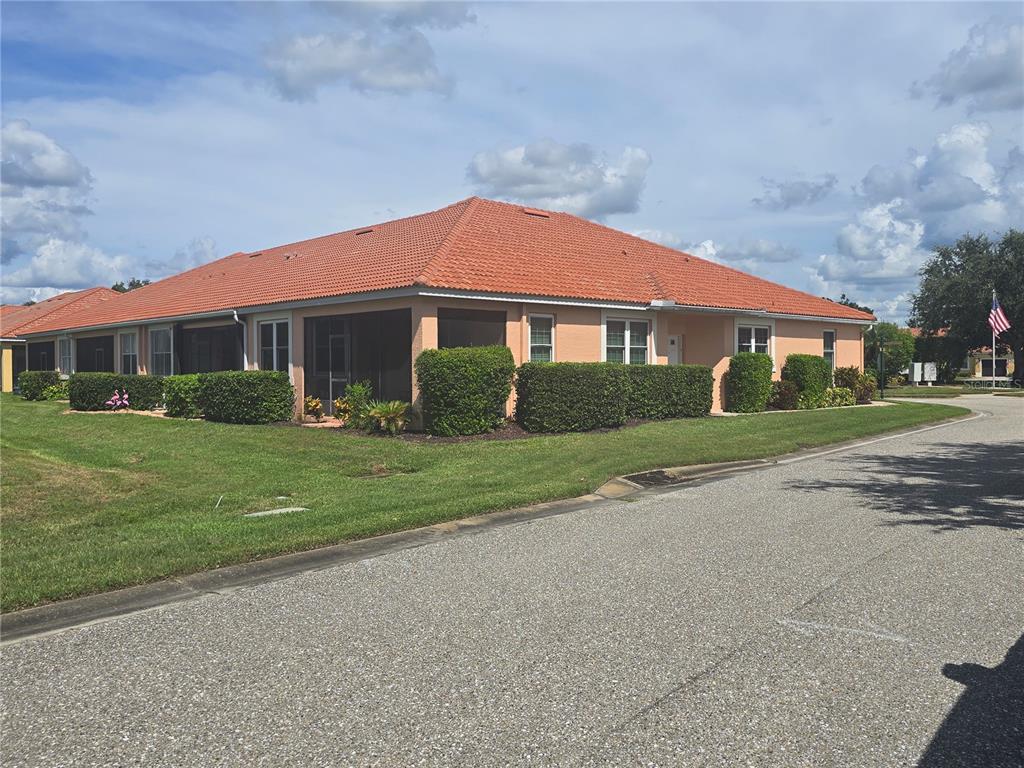 A single-story peach-colored villa features a red tile roof and a screened-in patio area — 9007 VISTA VERDE DRIVE, PALMETTO, FL