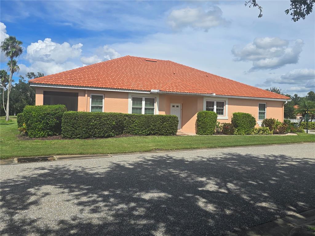 A single-story peach-colored house with a red tile roof and manicured hedges — 9007 VISTA VERDE DRIVE, PALMETTO, FL