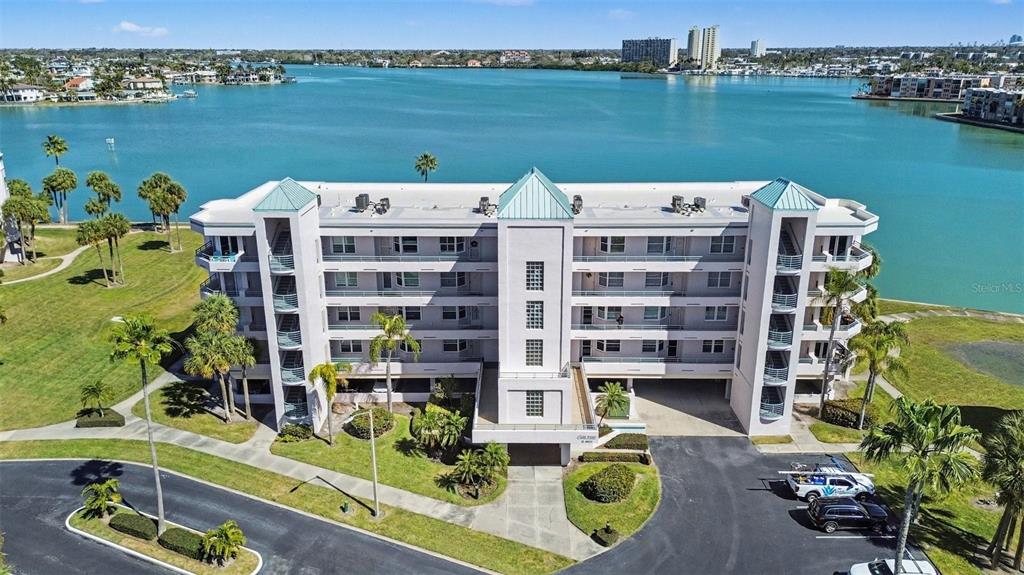 An aerial view of a multi-story waterfront apartment building with a parking lot and landscaping — 8021 SAILBOAT KEY BOULEVARD S UNIT 304, ST PETE BEACH, FL