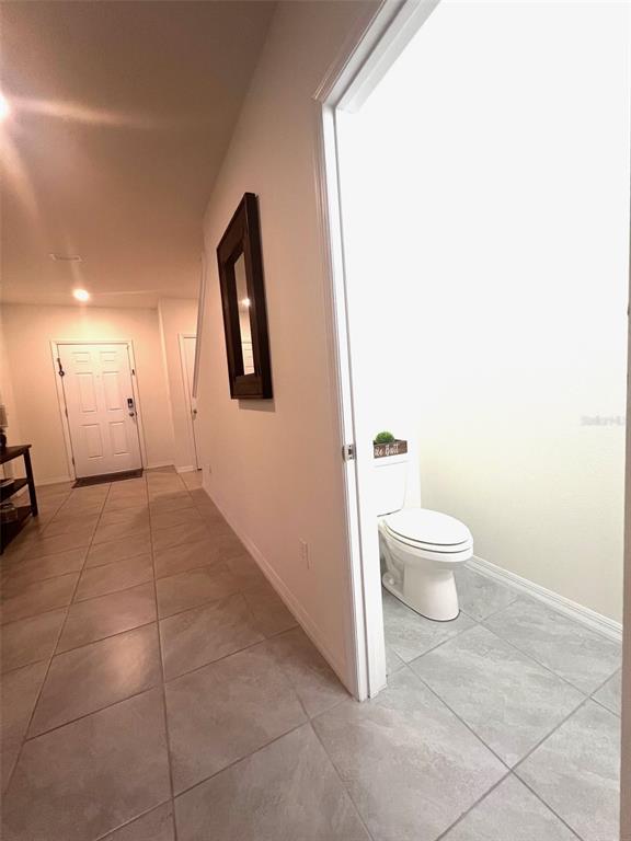 A tiled hallway leads to a front door and a small bathroom with a toilet — 9033 ALBA LANE, KISSIMMEE, FL