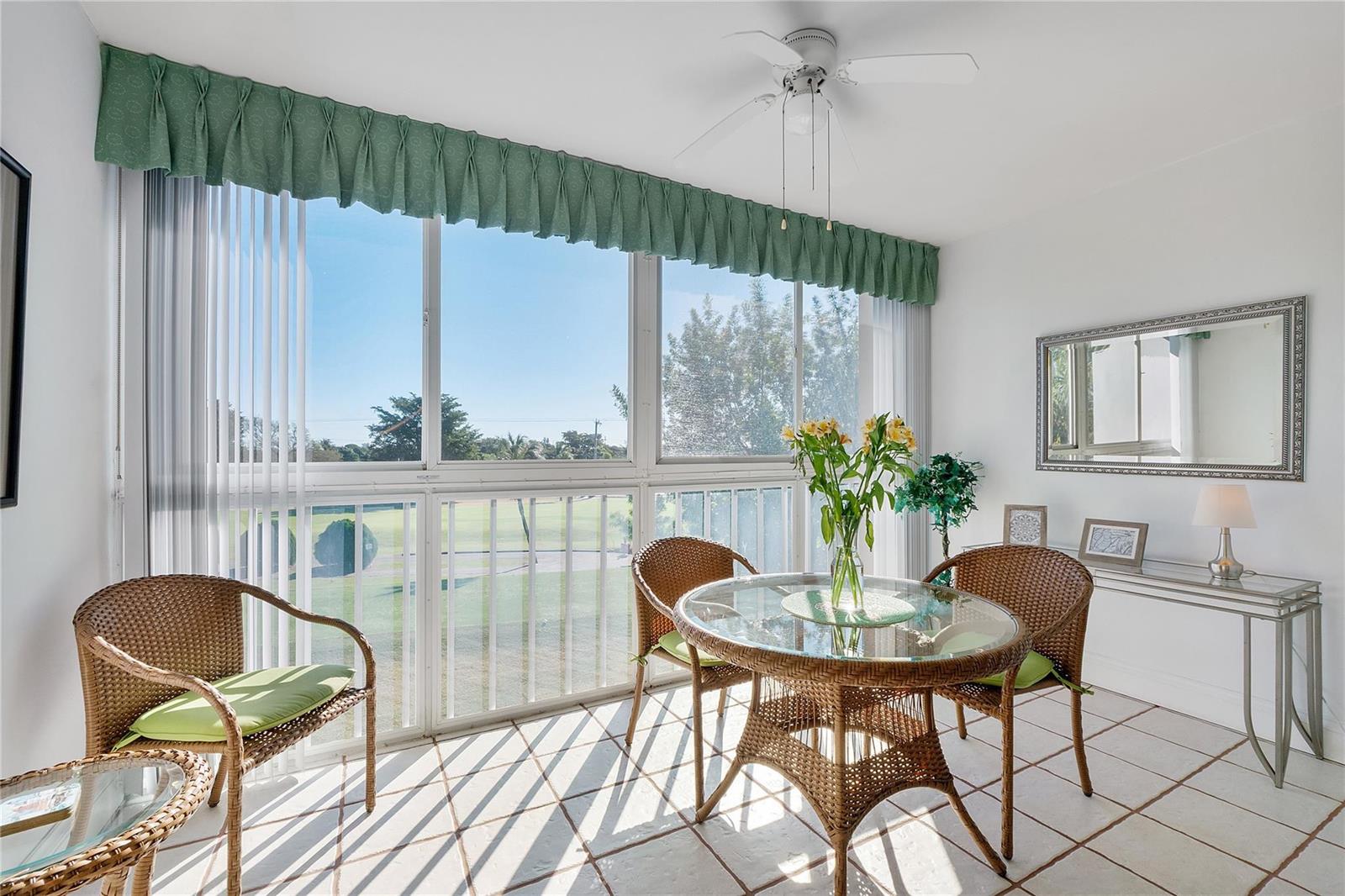 A sunroom features wicker chairs, a glass-top table, tile flooring, and views of a golf course — 7787 Golf Circle Drive # 312, Margate FL 33063, MARGATE, FL