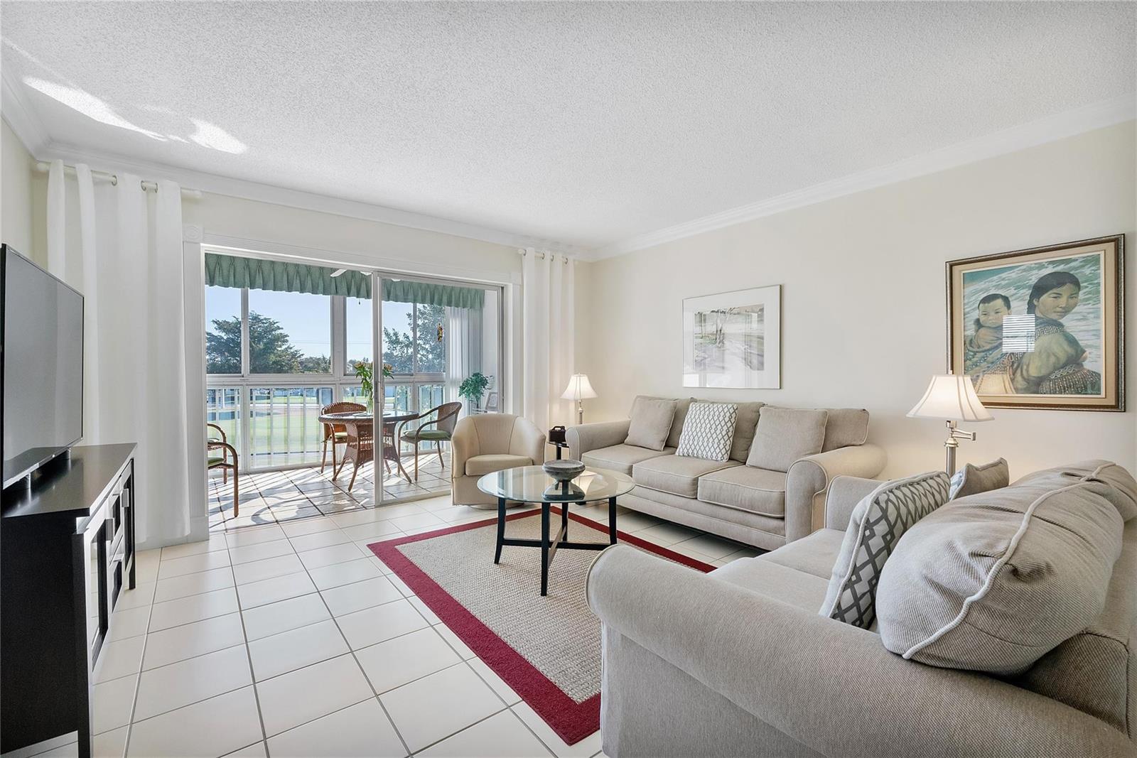 A living room features tile floors, two beige sofas, a glass coffee table, and balcony access — 7787 Golf Circle Drive # 312, Margate FL 33063, MARGATE, FL