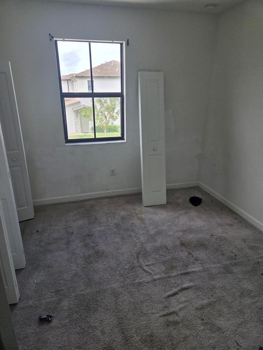 An empty bedroom features gray carpeting, white walls, a single window, and detached closet doors — 23317 SW 129th Path, Homestead FL 33032, HOMESTEAD, FL