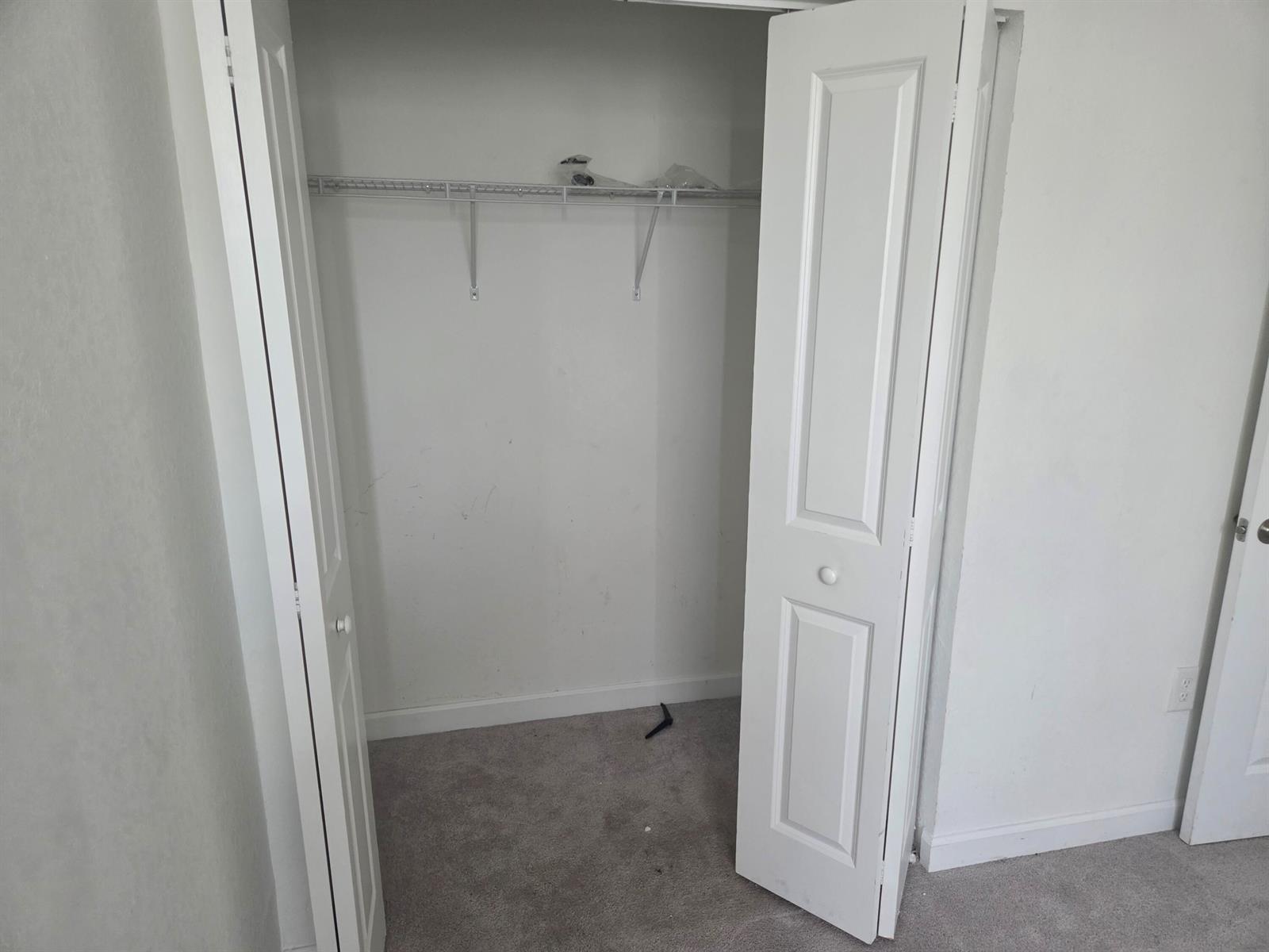 A small closet with a wire shelf and white bi-fold doors in a carpeted room — 23317 SW 129th Path, Homestead FL 33032, HOMESTEAD, FL